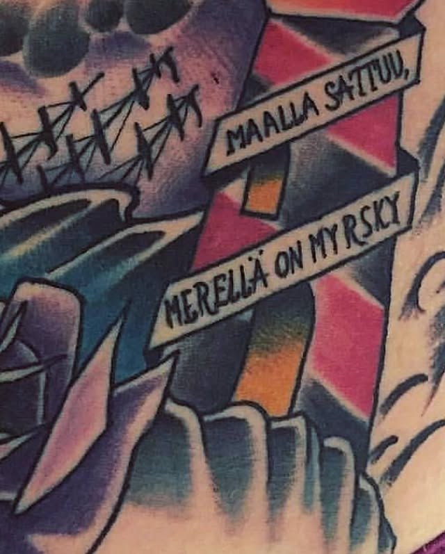 Värillinen majakkatatuointi, jonka banderolleissa lukee ”Maalla sattuu, merellä on myrsky”.